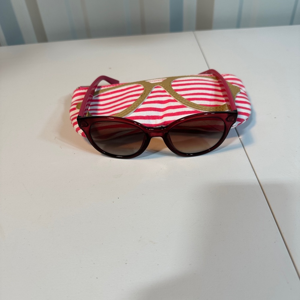 Pink women’s Lacoste sunglasses with pink striped carrying pouch
